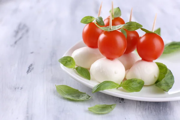 Gustosa mozzarella con basilico e pomodoro sul piatto, sul tavolo di legno — Foto Stock