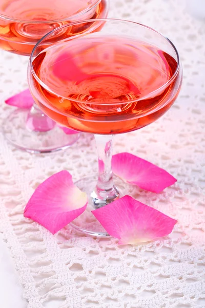 Composition with pink sparkle wine in glasses and rose petals isolated on white — Stock Photo, Image