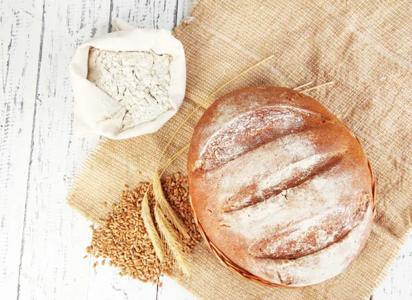 Roggebrood met meel en granen op rouwgewaad op houten achtergrond — Stockfoto