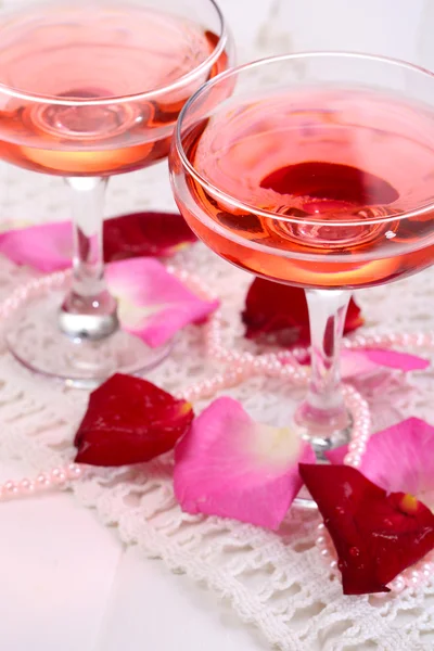 メガネでバラの花びらを白で隔離されるピンクの輝きのワインと組成 — ストック写真