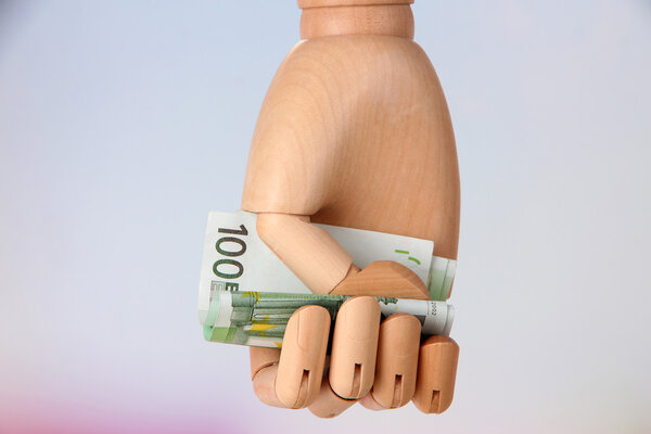 Деньги в деревянной руке, на светлом фоне
