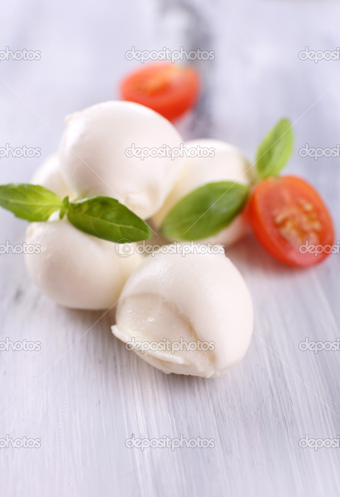 Tasty mozzarella cheese with basil and tomatoes, on wooden table