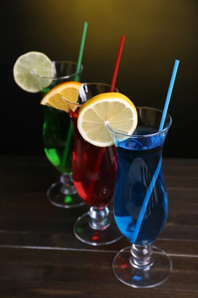 Glasses of cocktails on table on dark yellow background — Stock Photo, Image