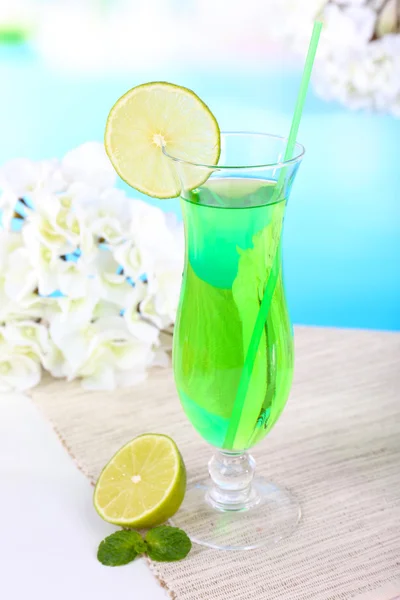 Glass of cocktail on table on light blue background — Stock Photo, Image