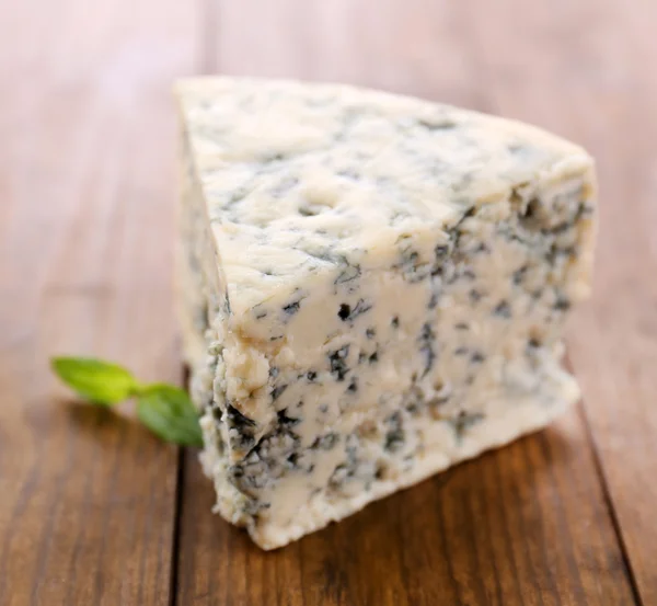 Tasty blue cheese with basil, on wooden table — Stock Photo, Image