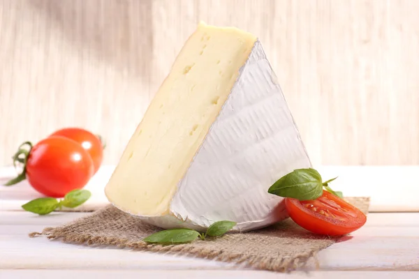 Sabroso queso Camembert con albahaca y tomates, sobre mesa de madera —  Fotos de Stock