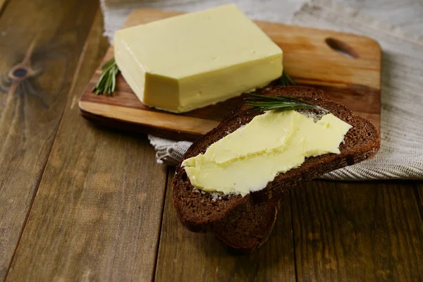 Rebanada de pan de centeno con mantequilla en tabla de cortar de madera — Foto de Stock