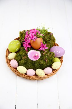 kavramsal Paskalya kompozisyon. ahşap zemin üzerine yumurta, yumurta ve dekoratif moss ve hasır mat, üzerinde çiçek mum yanan yakın çekim