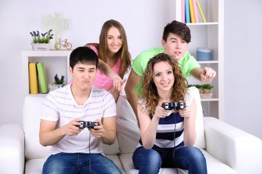 Group of young friends playing video games at home clipart