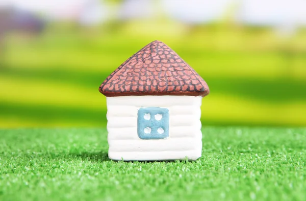 Piccola casa su erba verde, su sfondo luminoso — Foto Stock