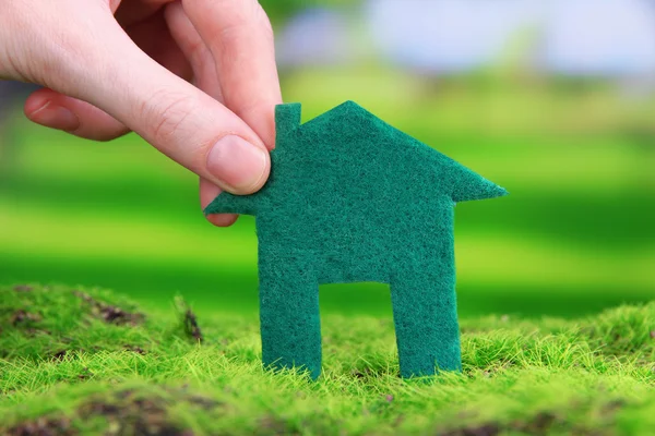 Little paper house in hand on green grass on bright background — Stock Photo, Image