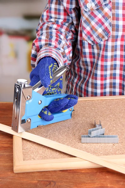 Fissaggio assicella di legno e tavola di sughero utilizzando cucitrice costruzione su sfondo luminoso — Foto Stock