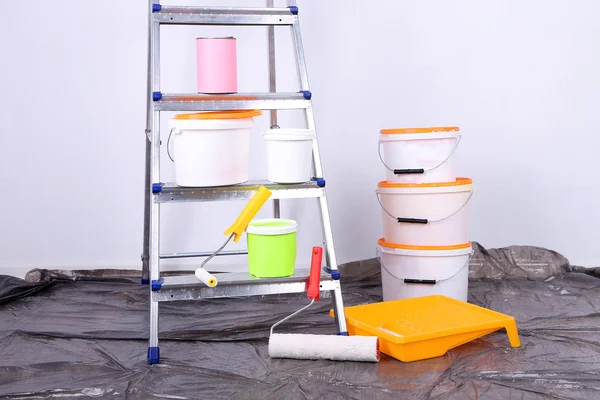 Cubos con pintura y escalera sobre fondo de pared. Foto conceptual de los trabajos de reparación en la habitación — Foto de Stock