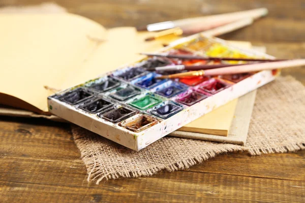 Composition with colorful watercolors, brushes and sketcher on wooden background — Stock Photo, Image