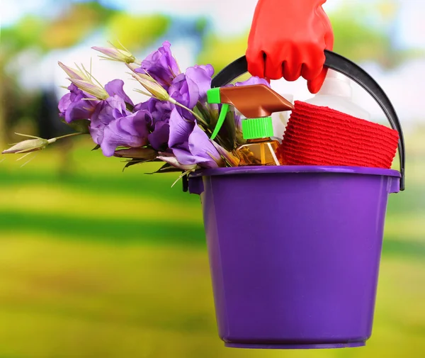 Ama de casa sosteniendo cubo con equipo de limpieza sobre fondo brillante. Foto conceptual de la limpieza de primavera . —  Fotos de Stock