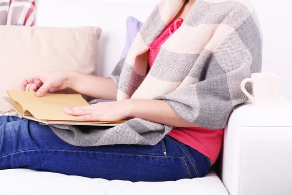Frau sitzt auf Sofa, liest Buch und trinkt Kaffee oder Tee, Nahaufnahme — Stockfoto