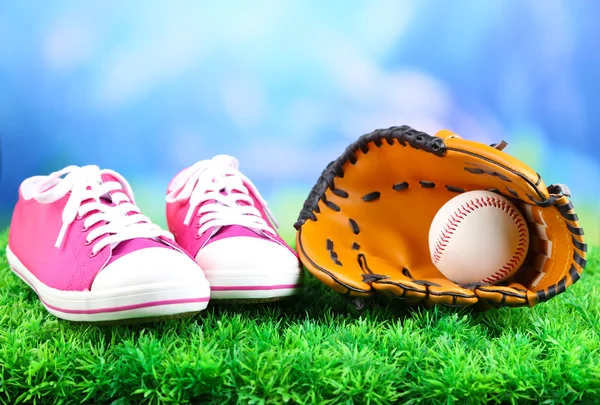 Vackra joggingskor och baseball boll, handsken på grönt gräs, på ljus bakgrund — Stockfoto
