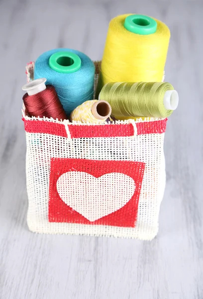 Colorful bobbins of thread  in bag, on wooden background — Stock Photo, Image