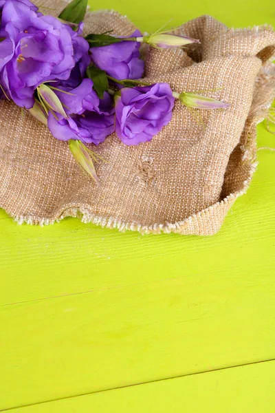 Fialové umělé eustoma v žíně na barevné dřevěné pozadí — Stock fotografie
