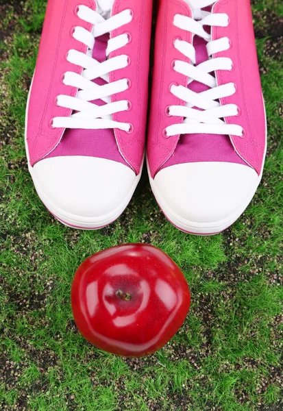 Vackra joggingskor och apple på grönt gräs bakgrund — Stockfoto