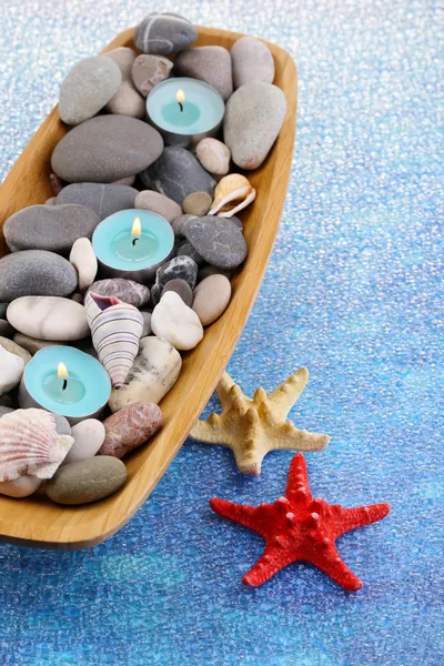 Wooden bowl with Spa stones, sea shells and candles on color background — Stock Photo, Image