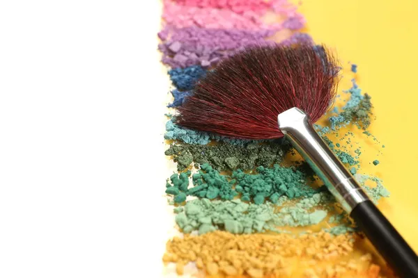 Arco-íris esmagado sombra e escova de maquiagem profissional no fundo amarelo — Fotografia de Stock