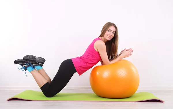 Jovem bela menina fitness exercitando com bola laranja no ginásio — Fotografia de Stock