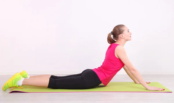 Young beautiful fitness girl exercising on green mat, in gym — Stock Photo, Image