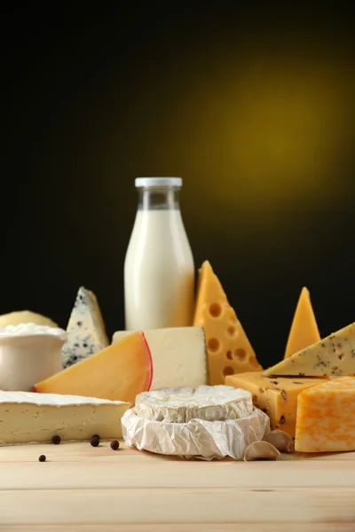 Tasty dairy products on wooden table, on dark background — Stock Photo, Image