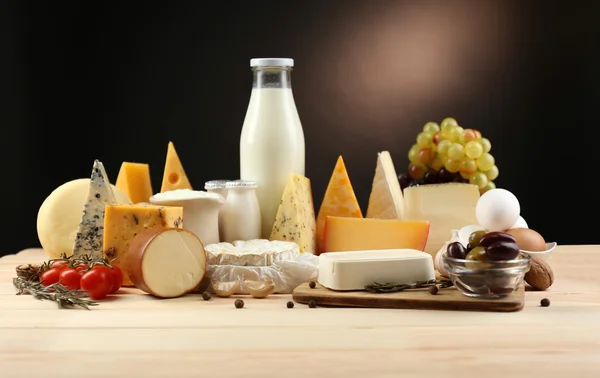 Productos lácteos sabrosos sobre mesa de madera, sobre fondo oscuro — Foto de Stock
