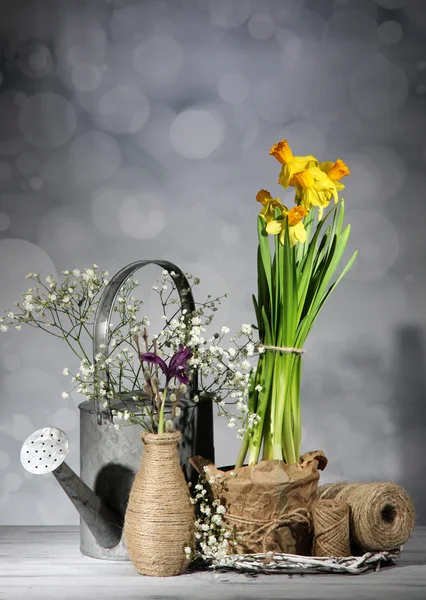Szép tavaszi virágok a régi fából készült asztal, a szürke háttér — Stock Fotó