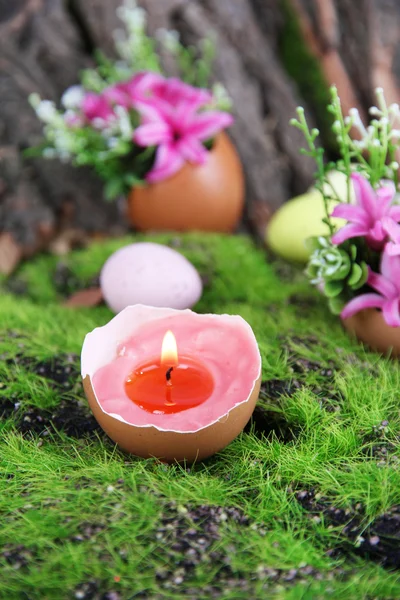 Konzeptionelle Osterkomposition. brennende Kerze im Ei und Blumen auf grünem Gras Hintergrund, Nahaufnahme — Stockfoto