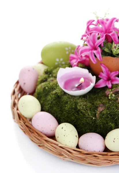 Composition conceptuelle de Pâques. Bougie brûlante dans l'oeuf, oeufs de Pâques, et des fleurs sur la mousse décorative et tapis d'osier, isolé sur blanc — Photo