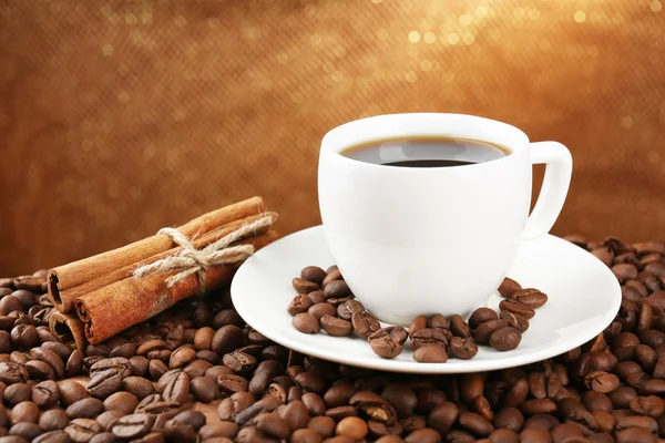 Grãos de café e xícara de café na mesa sobre fundo marrom — Fotografia de Stock