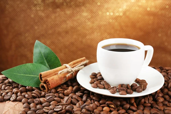 Coffee beans and cup of coffee on table on brown background — Stock Photo, Image