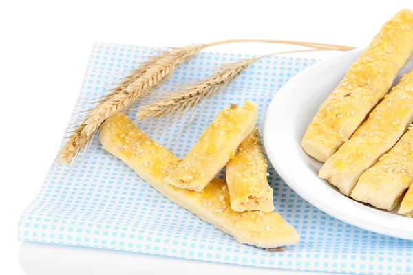 Gustosi bastoncini di pane su piatto su tovagliolo di colore, isolati su bianco — Foto Stock