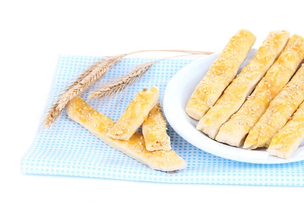 Gustosi bastoncini di pane su piatto su tovagliolo di colore, isolati su bianco — Foto Stock