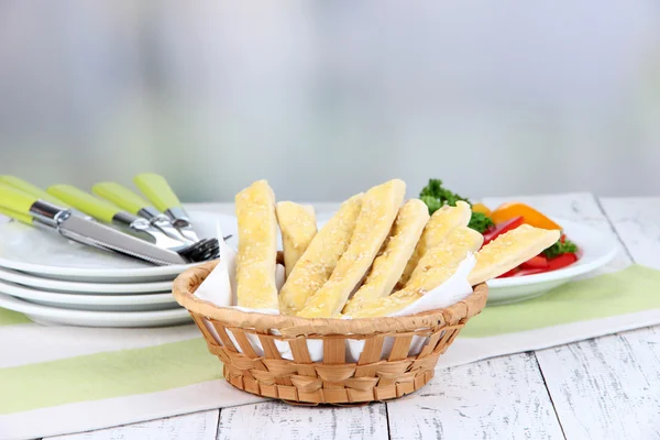 Palitos de pan en canasta de mimbre sobre mesa de madera sobre fondo claro —  Fotos de Stock