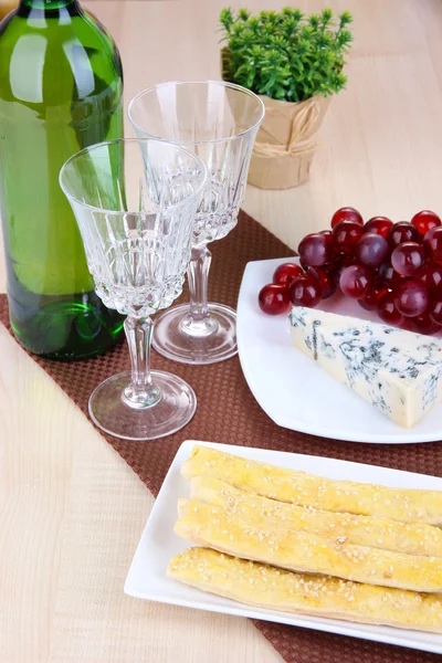 Τυρί, σταφυλιών και ψωμί μπαστούνια στο πιάτο σε ξύλινο τραπέζι φόντο — Φωτογραφία Αρχείου
