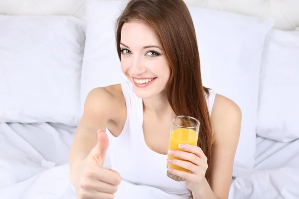 Mulher bonita nova com suco de laranja na cama close-up — Fotografia de Stock