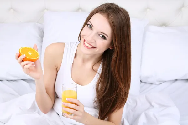 Mulher bonita nova com suco de laranja na cama close-up — Fotografia de Stock