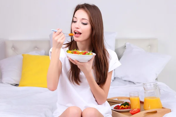 Young beautiful woman on bed with light breakfast — Stockfoto