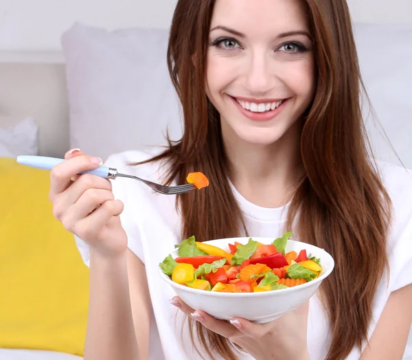 Unga vackra kvinnan på sängen med frisk sallad — Stockfoto