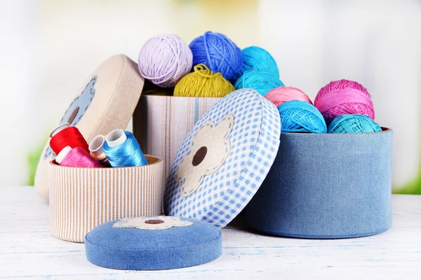 Decorative boxes with colorful skeins of thread on table on bright background — Stock Photo, Image