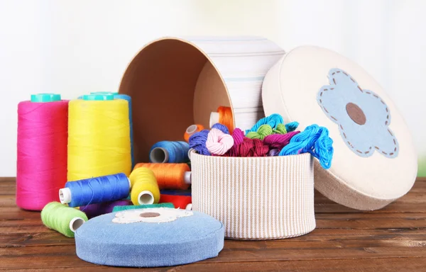 Decorative boxes with colorful skeins of thread on table on bright background — Stock Photo, Image