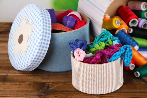 Decorative boxes with colorful skeins of thread and zippers on table close up — Stock Photo, Image