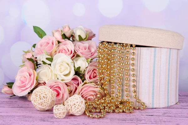 Caja decorativa con abalorios y flores en la mesa sobre fondo brillante — Foto de Stock