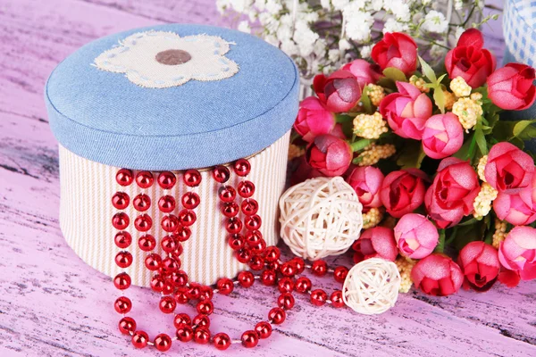 Decorative box with beads and flowers on wooden background — Stock Photo, Image