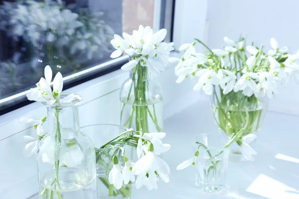 Beautiful bouquets of snowdrops in vases on windowsill — Stock Photo, Image