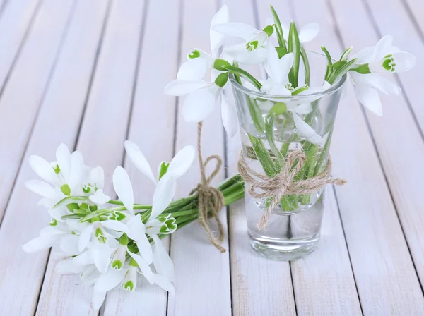 Beautiful bouquets of snowdrops in vases on wooden background — Stock Photo, Image